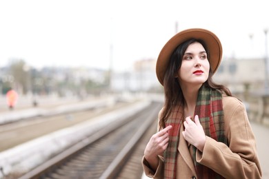 Photo of Beautiful woman in hat at railway station, space for text