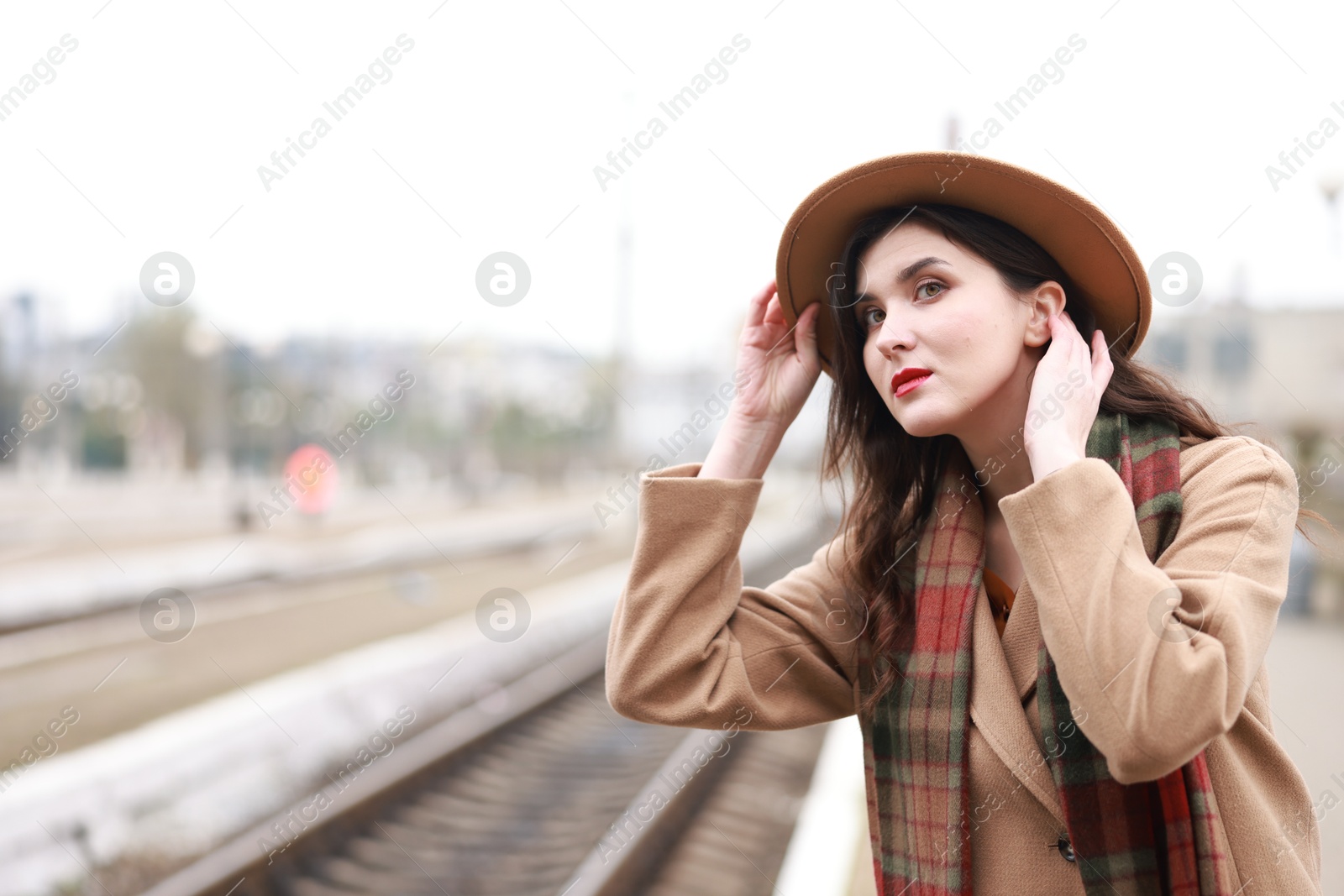 Photo of Beautiful woman in hat at railway station, space for text