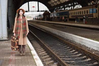 Photo of Beautiful woman with suitcase at railway station