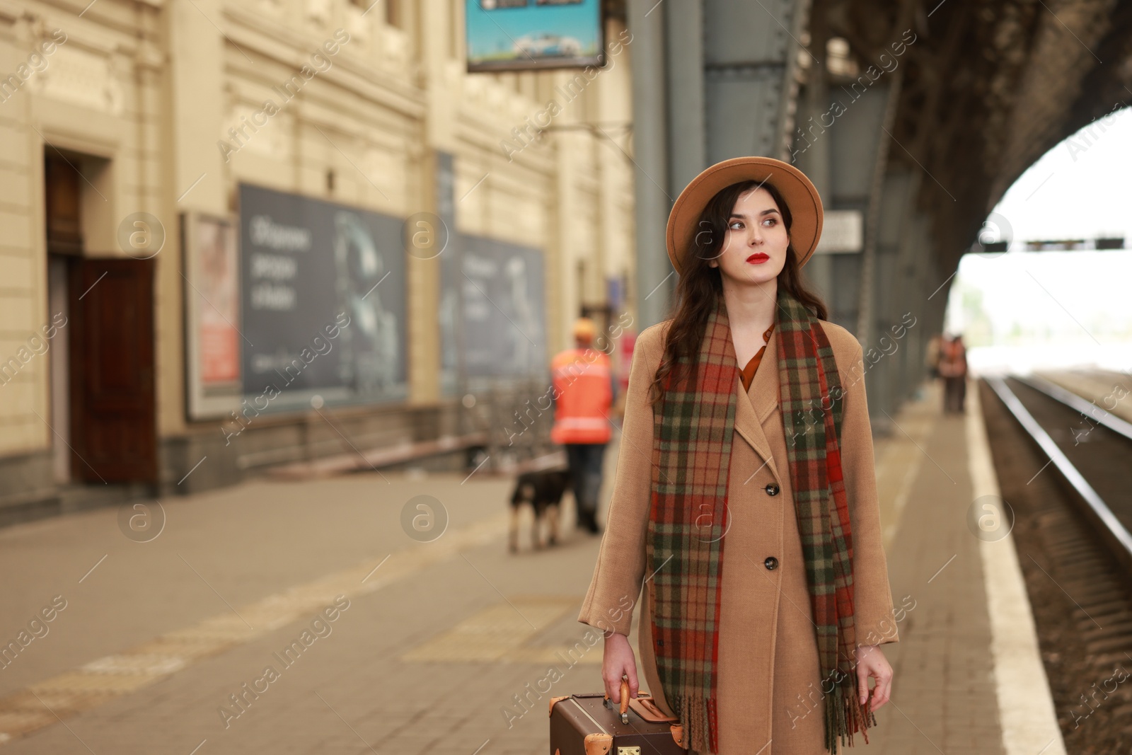 Photo of Beautiful woman with suitcase at railway station, space for text