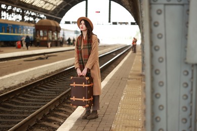 Photo of Beautiful woman with suitcase at railway station