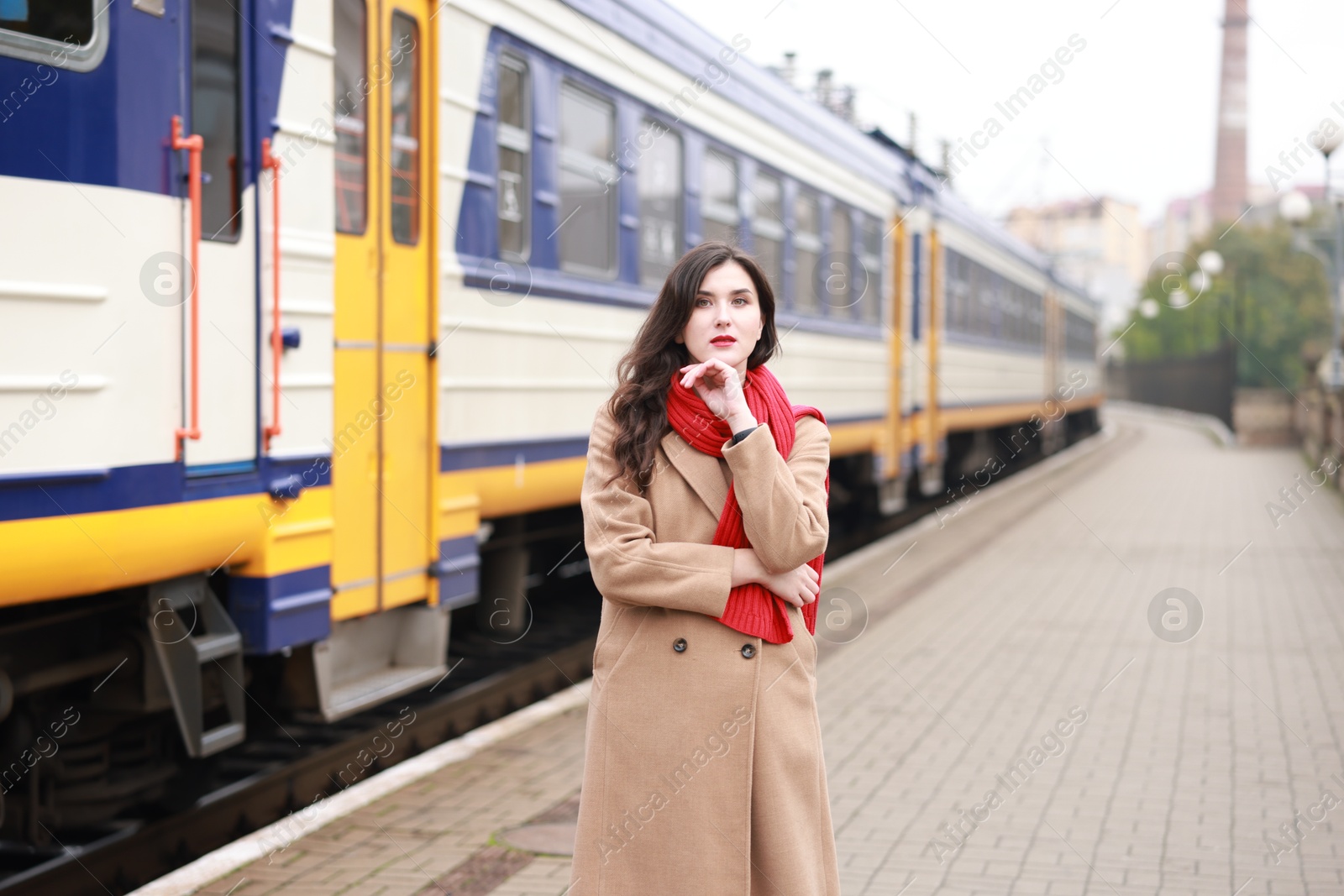 Photo of Woman with red scarf near train on platform of railway station