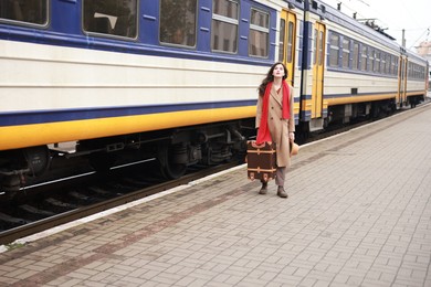 Photo of Woman with suitcase near train on platform of railway station