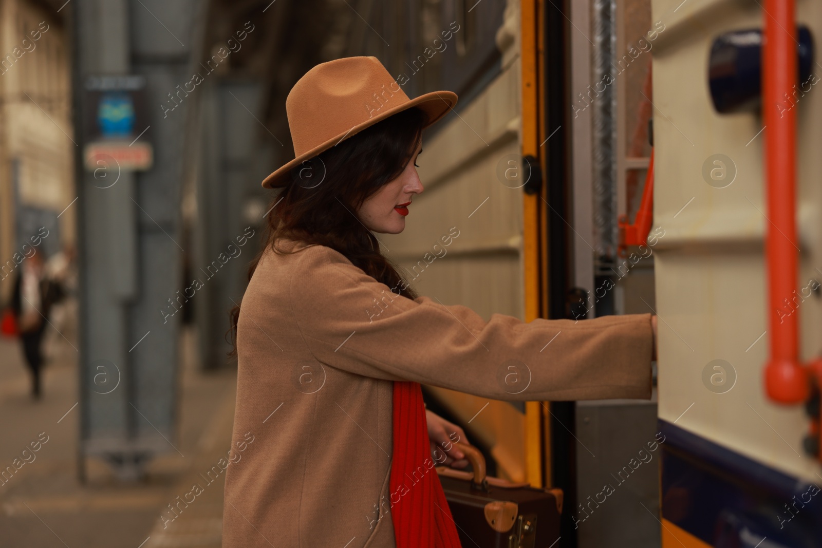 Photo of Woman with suitcase getting into train at railway station