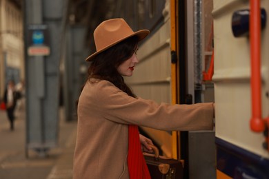 Woman with suitcase getting into train at railway station