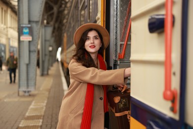 Woman with suitcase getting into train at railway station