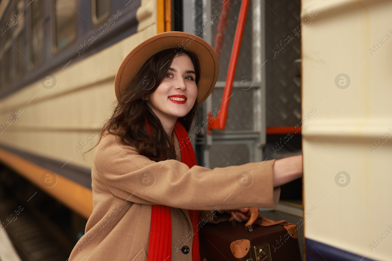 Photo of Woman with suitcase getting into train at railway station