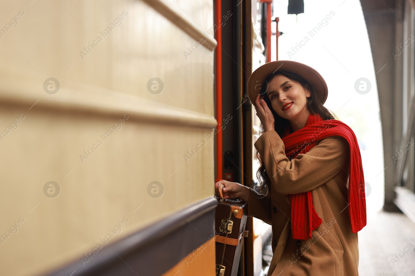 Photo of Woman with suitcase getting into train at railway station