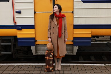 Photo of Woman with suitcase near train on platform of railway station