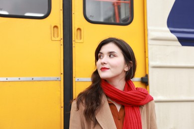 Photo of Beautiful woman with red scarf near train outdoors