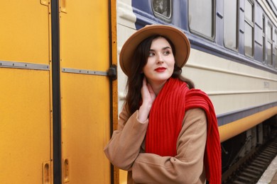 Photo of Beautiful woman with red scarf near train outdoors