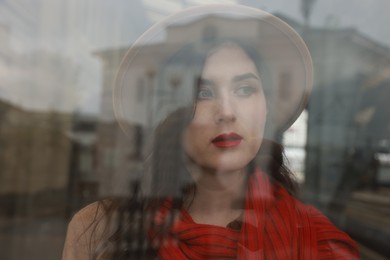 Photo of Woman with red scarf at railway station, view through glass window