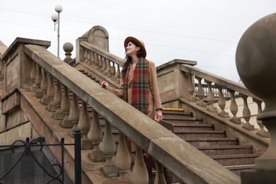 Photo of Beautiful woman with suitcase on stairs outdoors