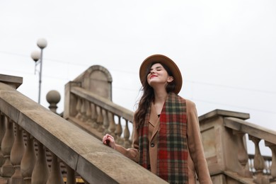 Beautiful woman with suitcase on stairs outdoors