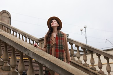 Photo of Beautiful woman with suitcase on stairs outdoors