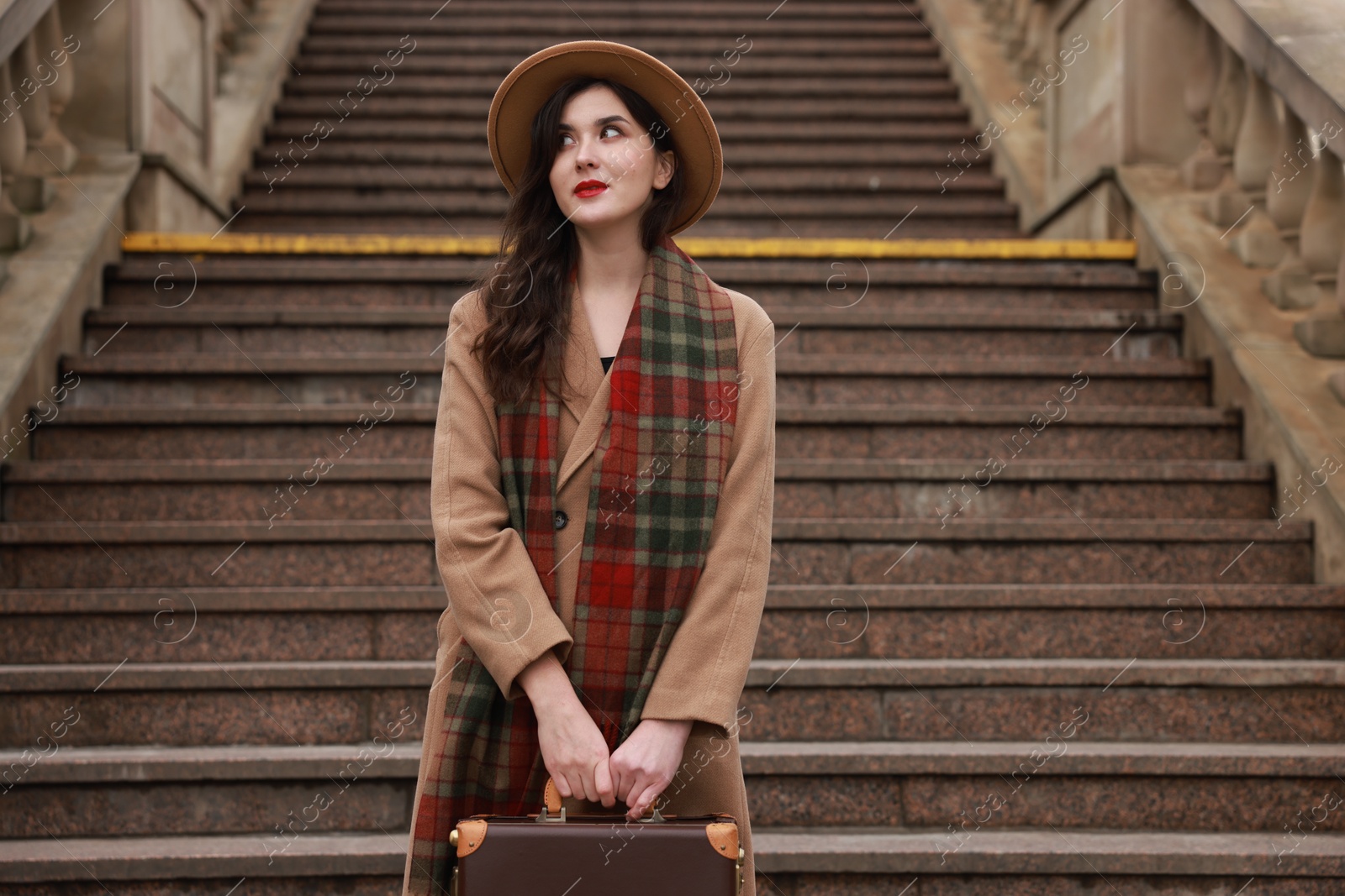 Photo of Beautiful woman with suitcase on stairs outdoors