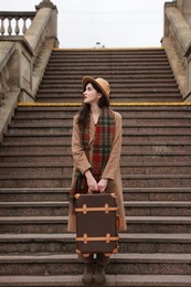 Photo of Beautiful woman with suitcase on stairs outdoors