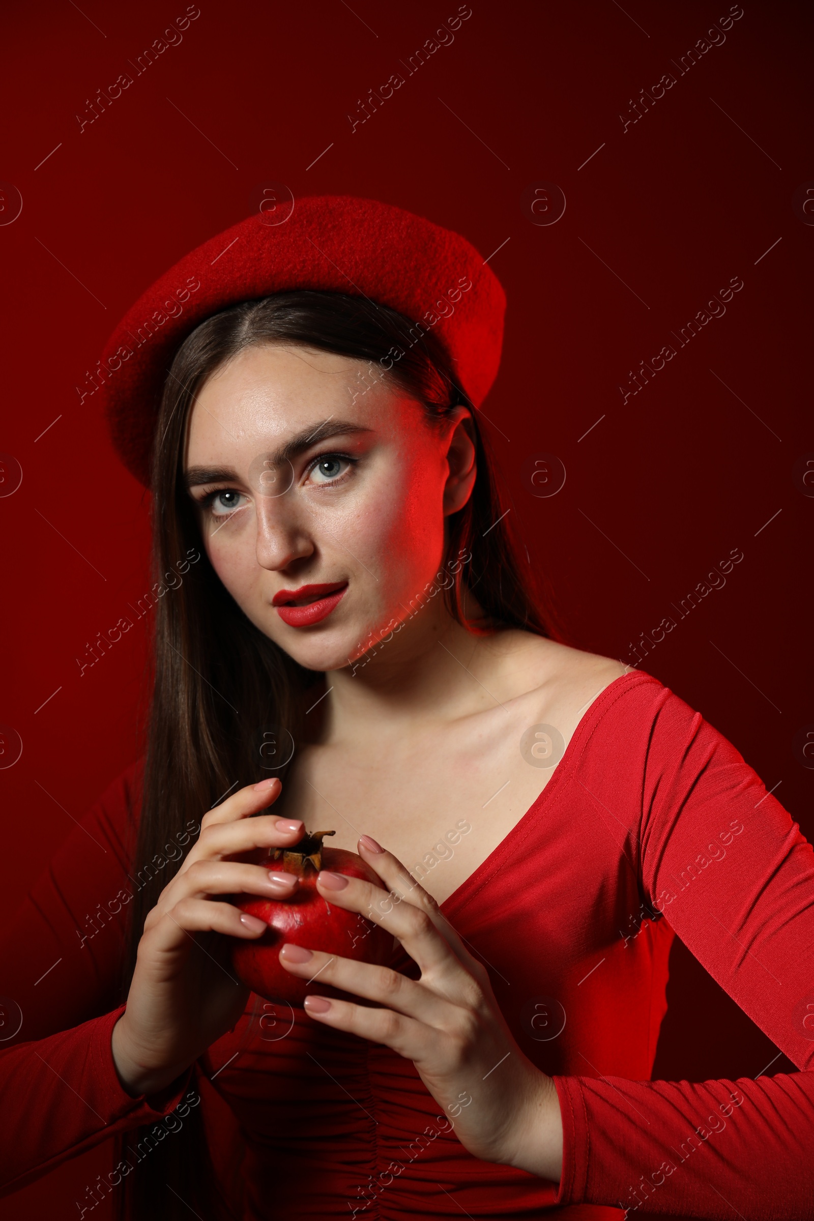 Photo of Woman with ripe pomegranate on red background