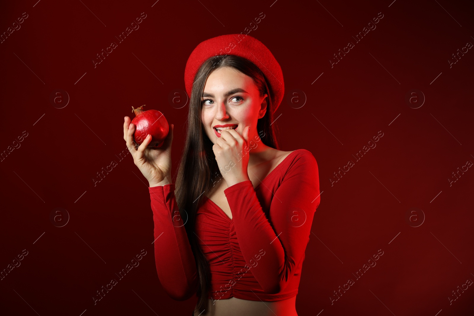 Photo of Woman with ripe pomegranate on red background