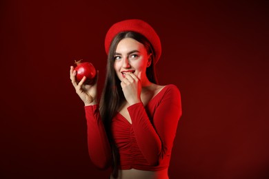 Photo of Woman with ripe pomegranate on red background