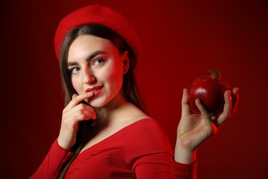 Photo of Woman with ripe pomegranate on red background