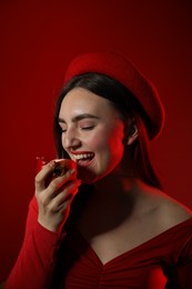 Woman eating ripe pomegranate on red background