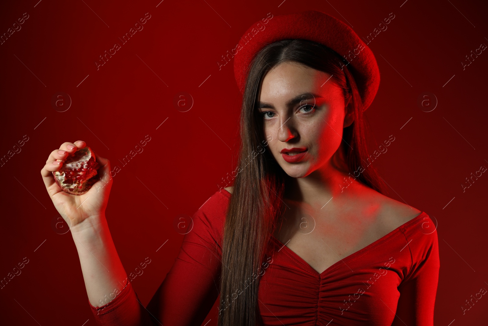 Photo of Woman with ripe pomegranate on red background