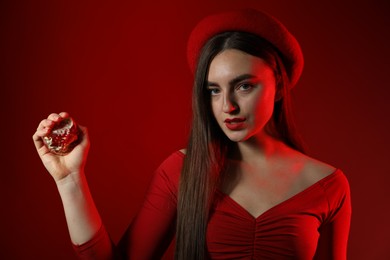 Woman with ripe pomegranate on red background