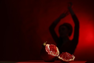 Photo of Woman posing against dark red background, focus on ripe pomegranate, space for text