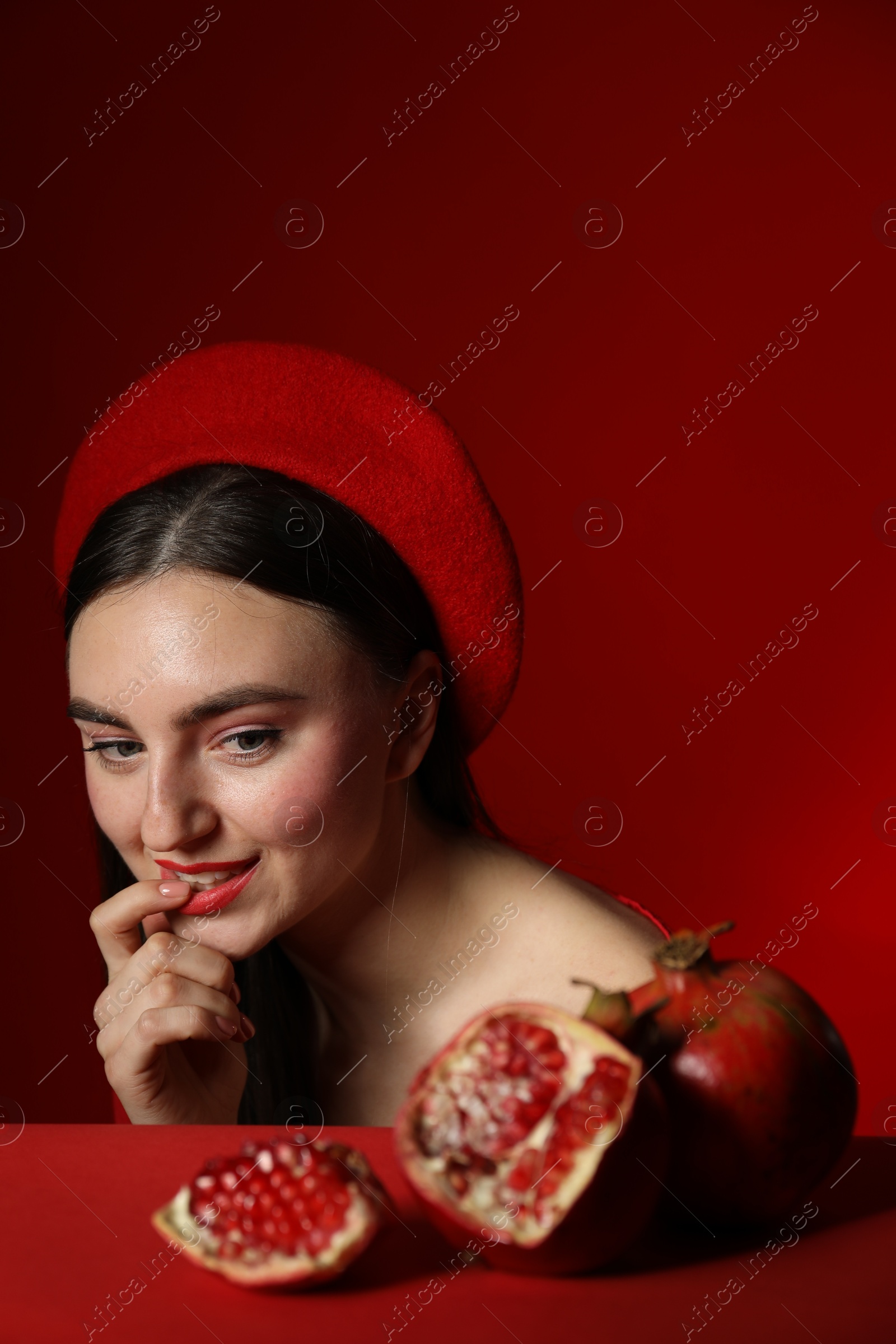 Photo of Woman with ripe pomegranate on red background