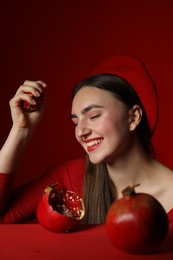 Woman with ripe pomegranate on red background