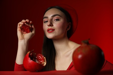 Woman with ripe pomegranate on red background