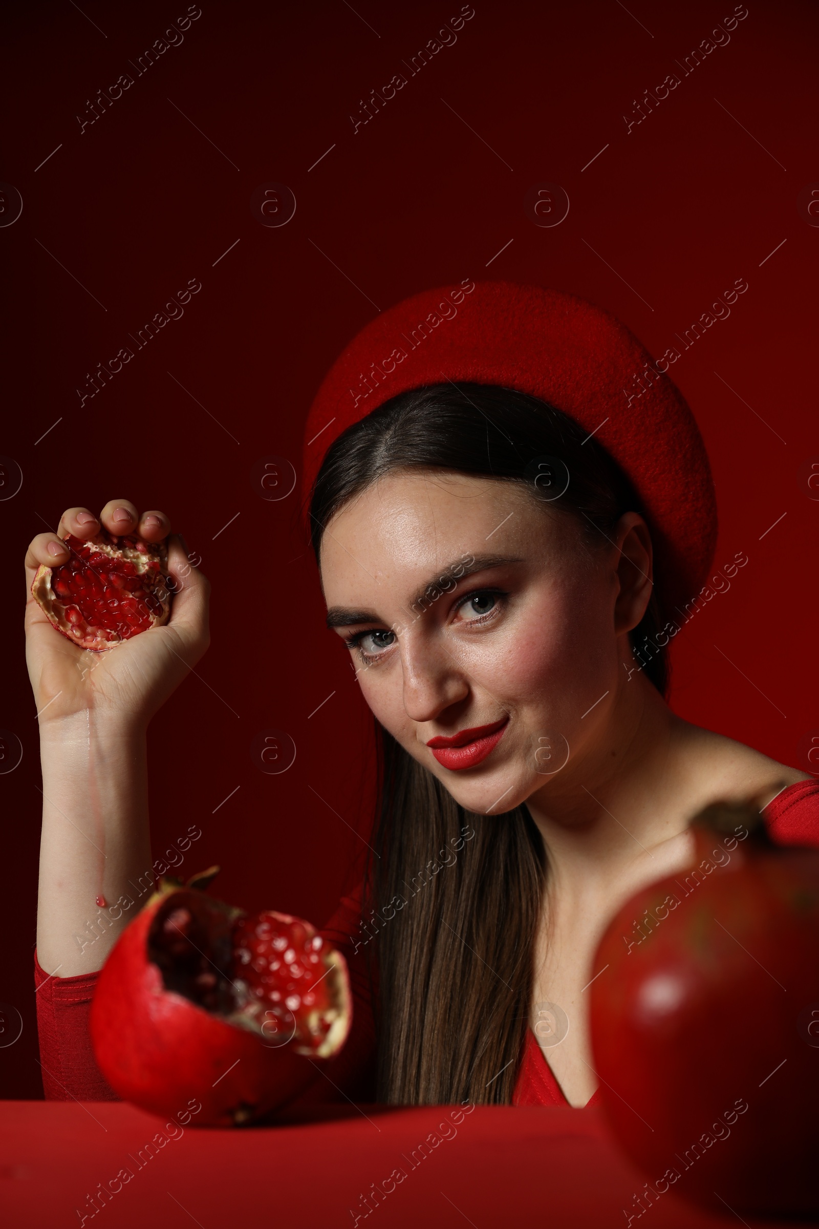 Photo of Woman with ripe pomegranate on red background