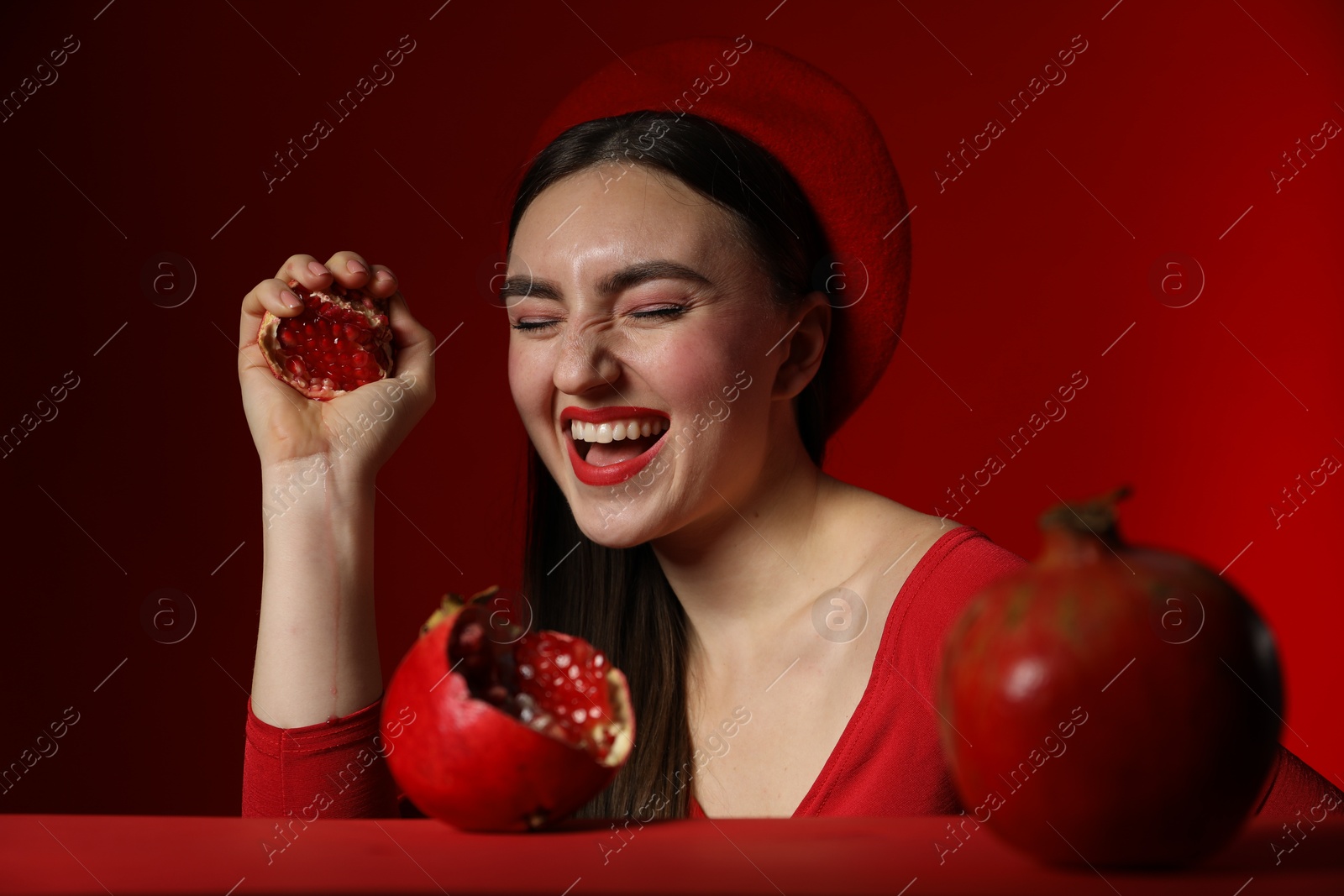 Photo of Woman with ripe pomegranate on red background