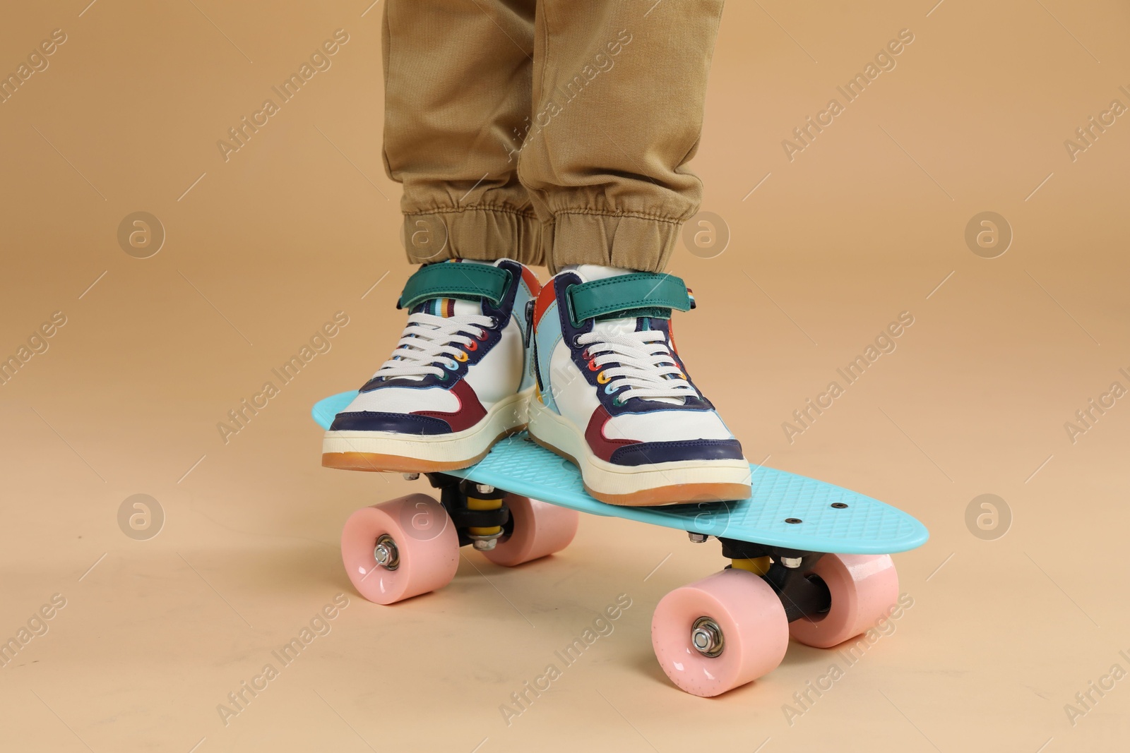 Photo of Little boy with skateboard on beige background, closeup