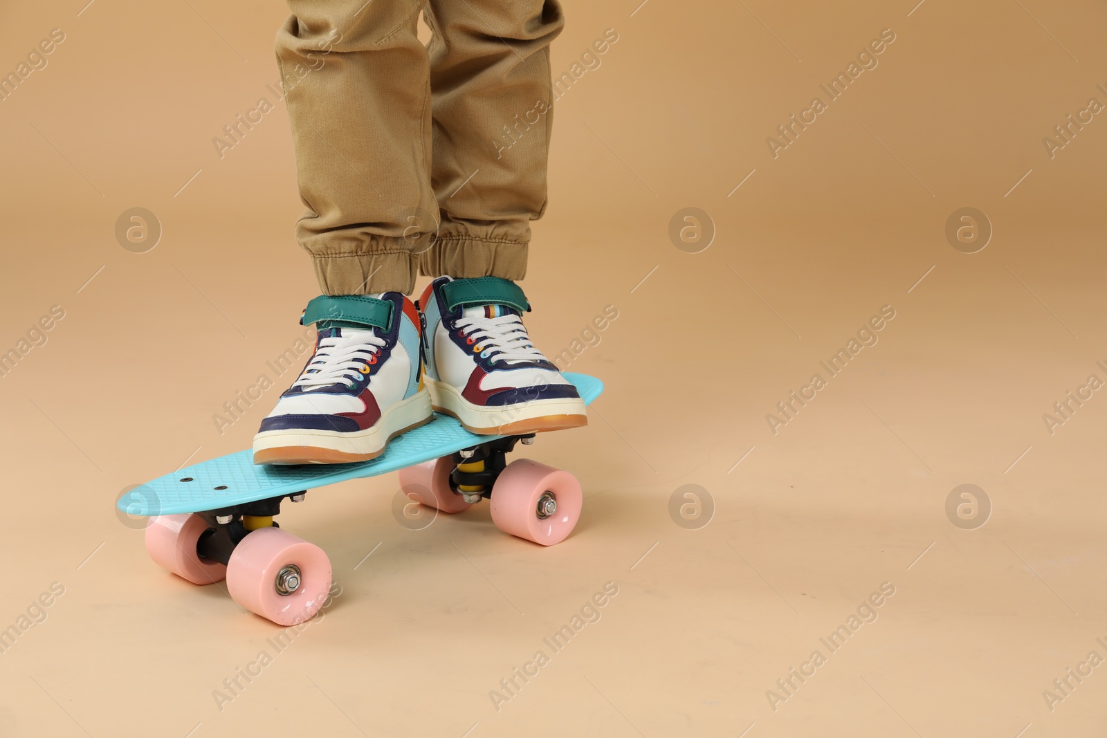 Photo of Little boy with skateboard on beige background, closeup. Space for text