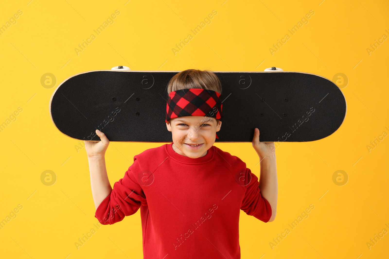 Photo of Little boy with skateboard on yellow background