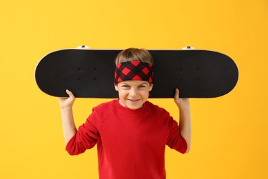 Photo of Little boy with skateboard on yellow background