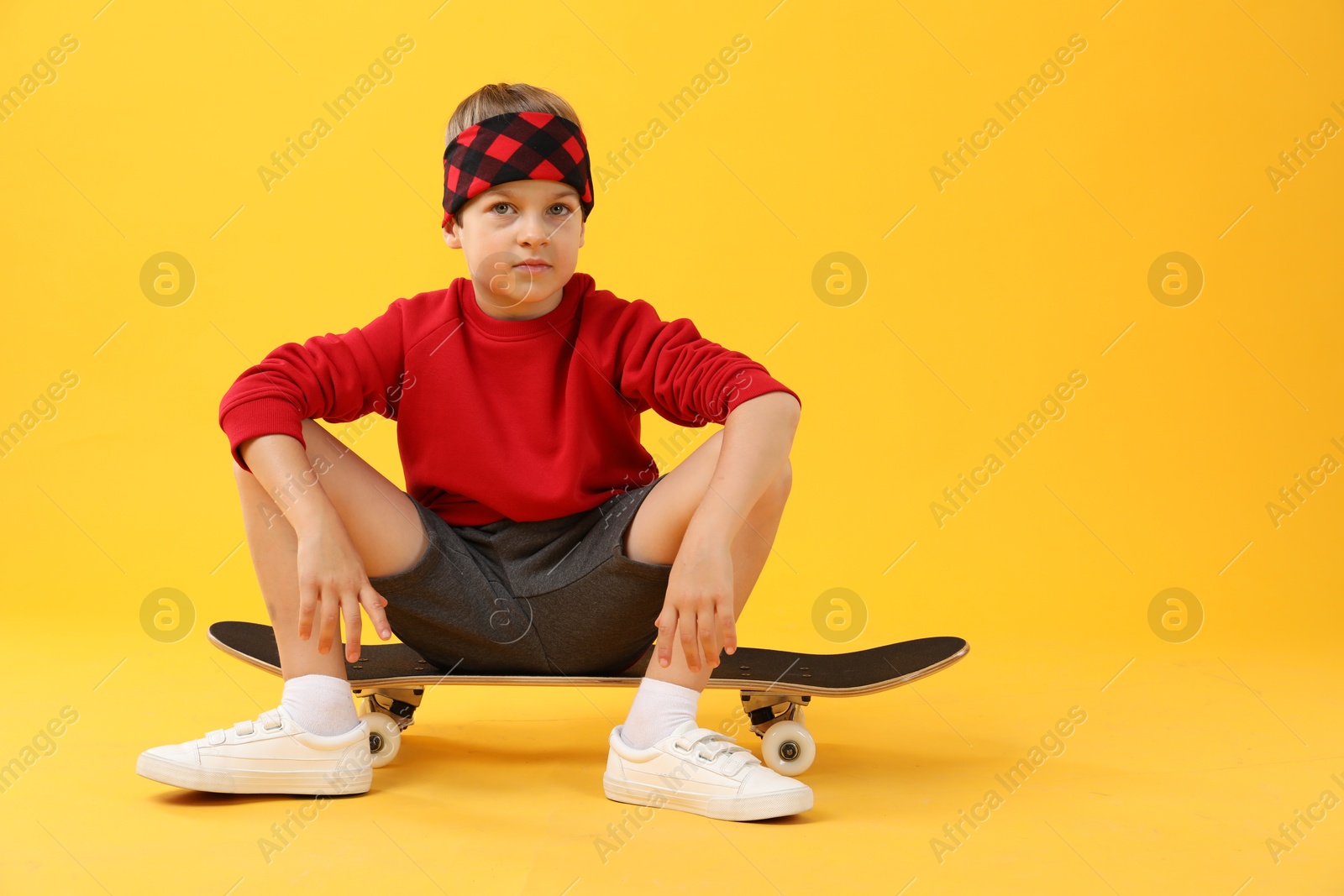 Photo of Little boy with skateboard on yellow background