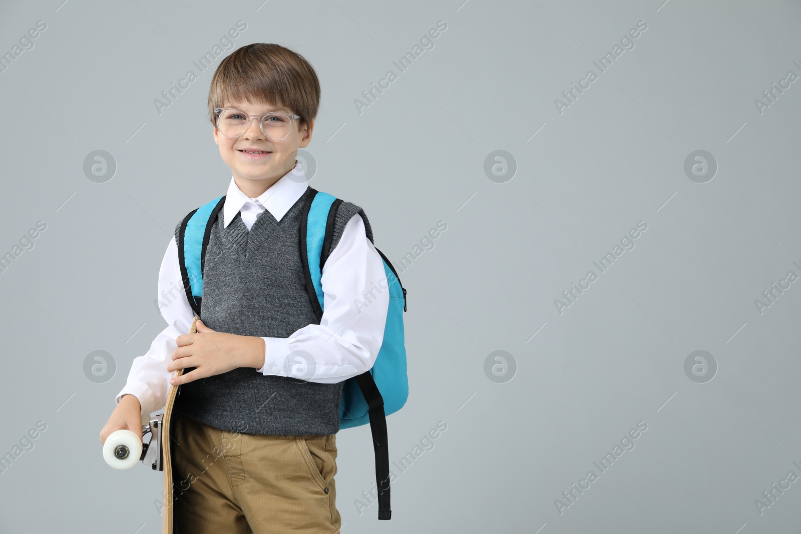 Photo of Little boy with skateboard on light grey background, space for text