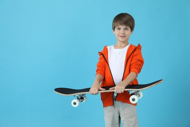 Little boy with skateboard on light blue background