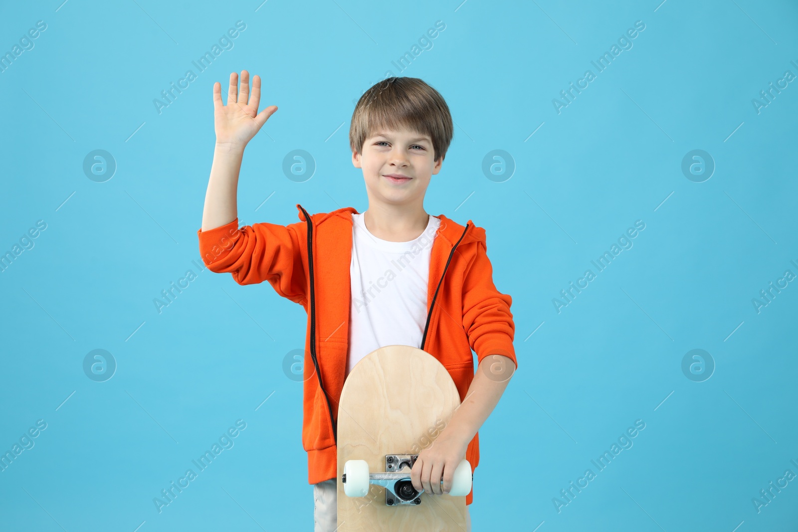 Photo of Little boy with skateboard on light blue background