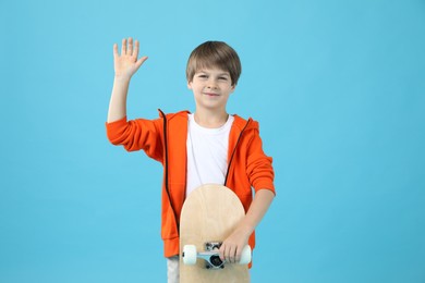 Little boy with skateboard on light blue background