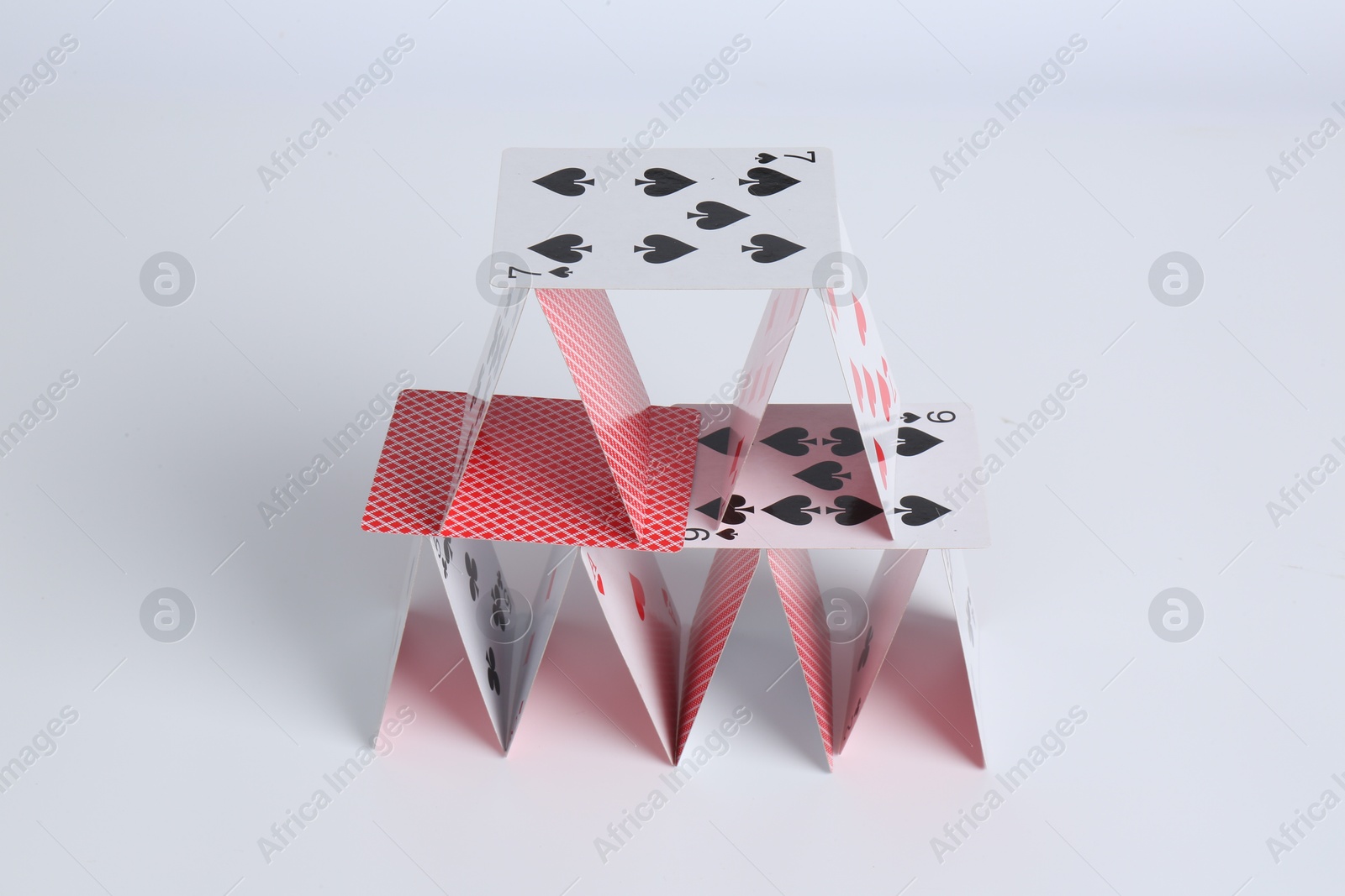 Photo of House of playing cards on white background