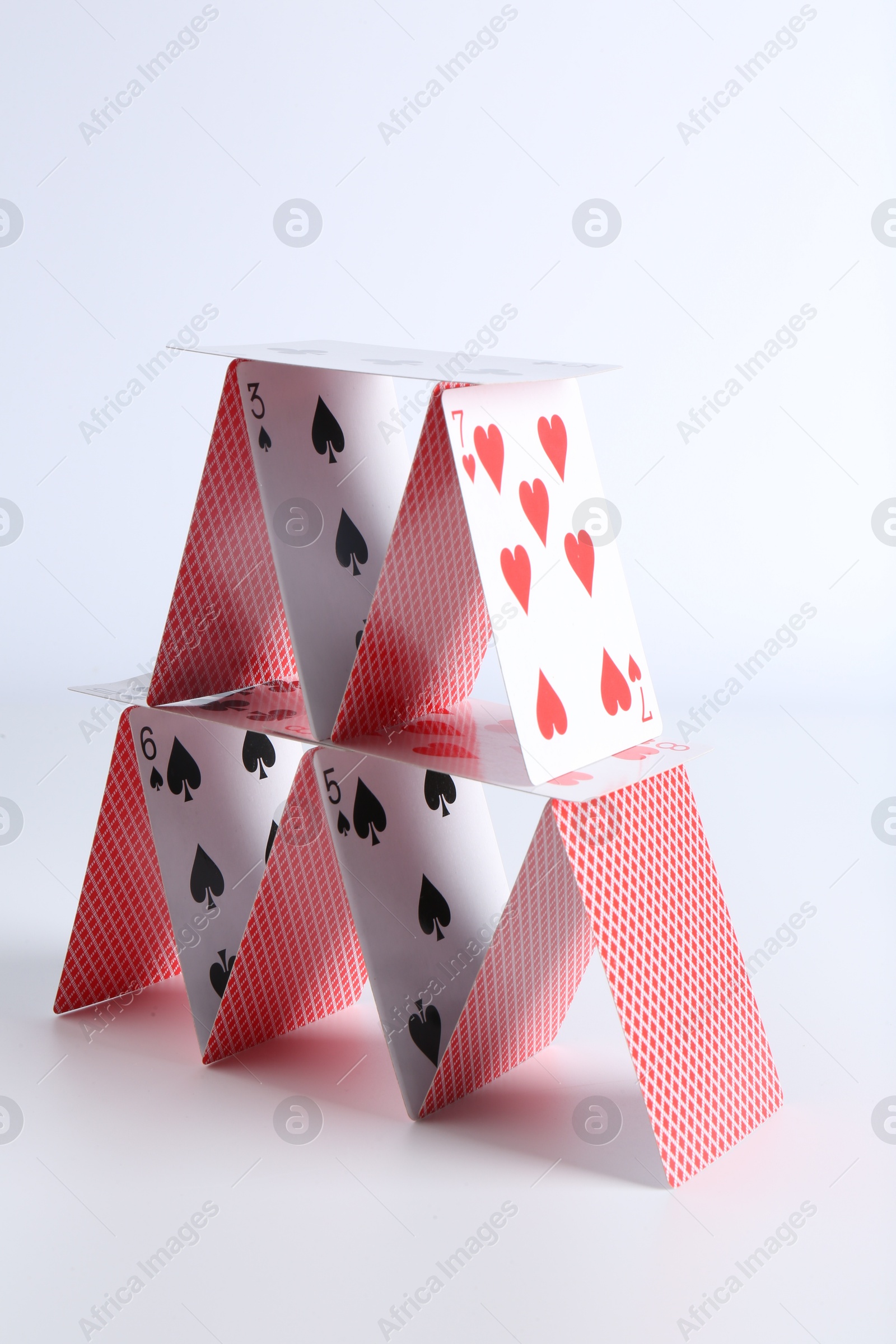 Photo of House of playing cards on white background