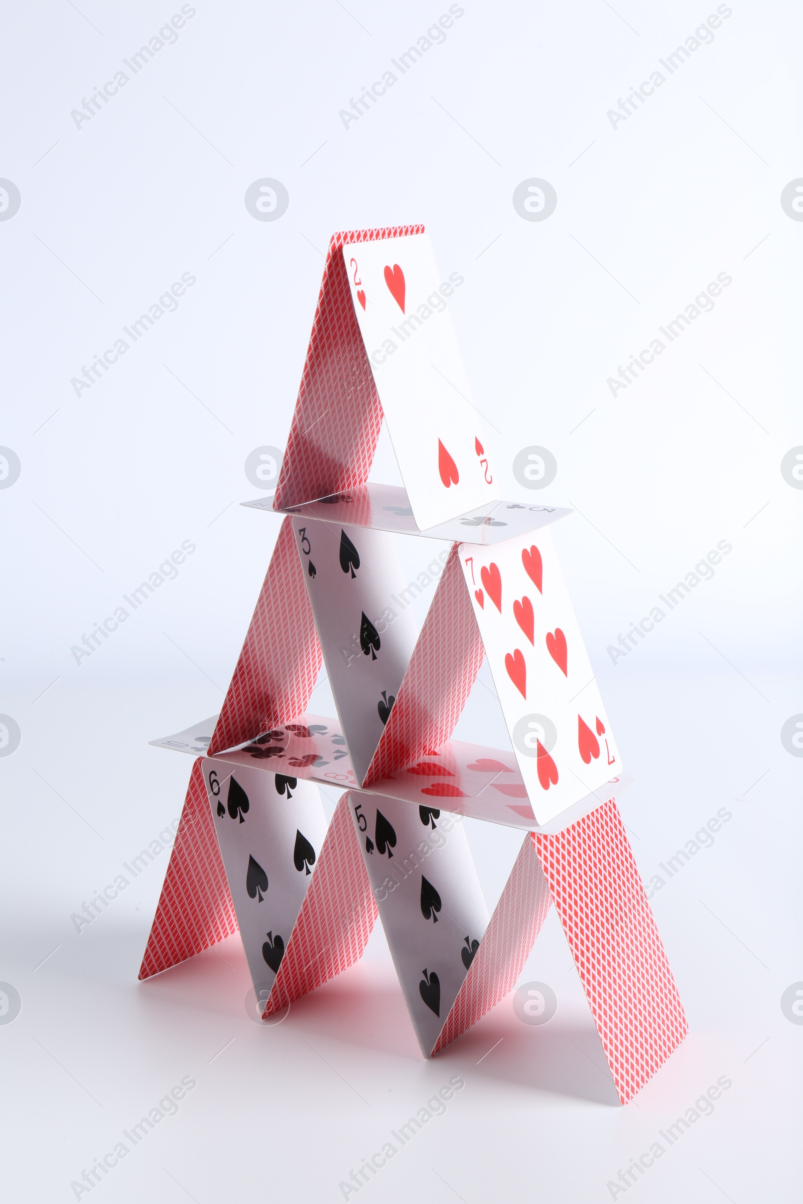 Photo of House of playing cards on white background