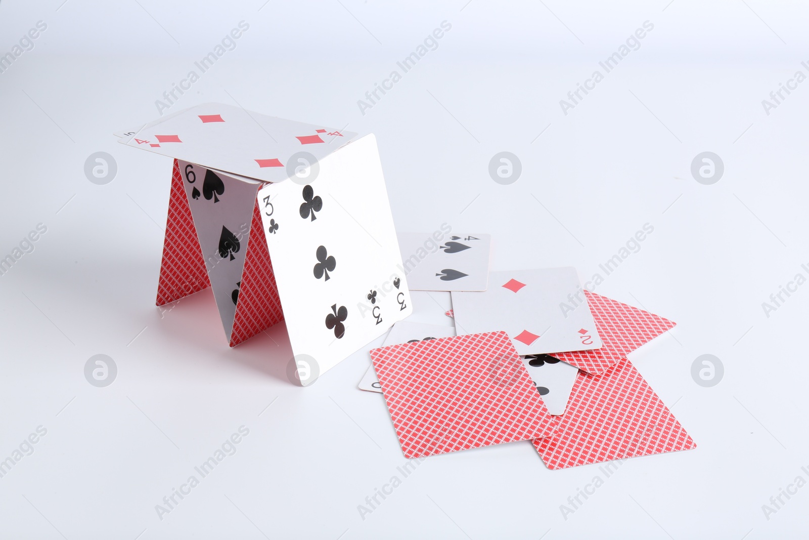 Photo of Collapsed house of playing cards on white background