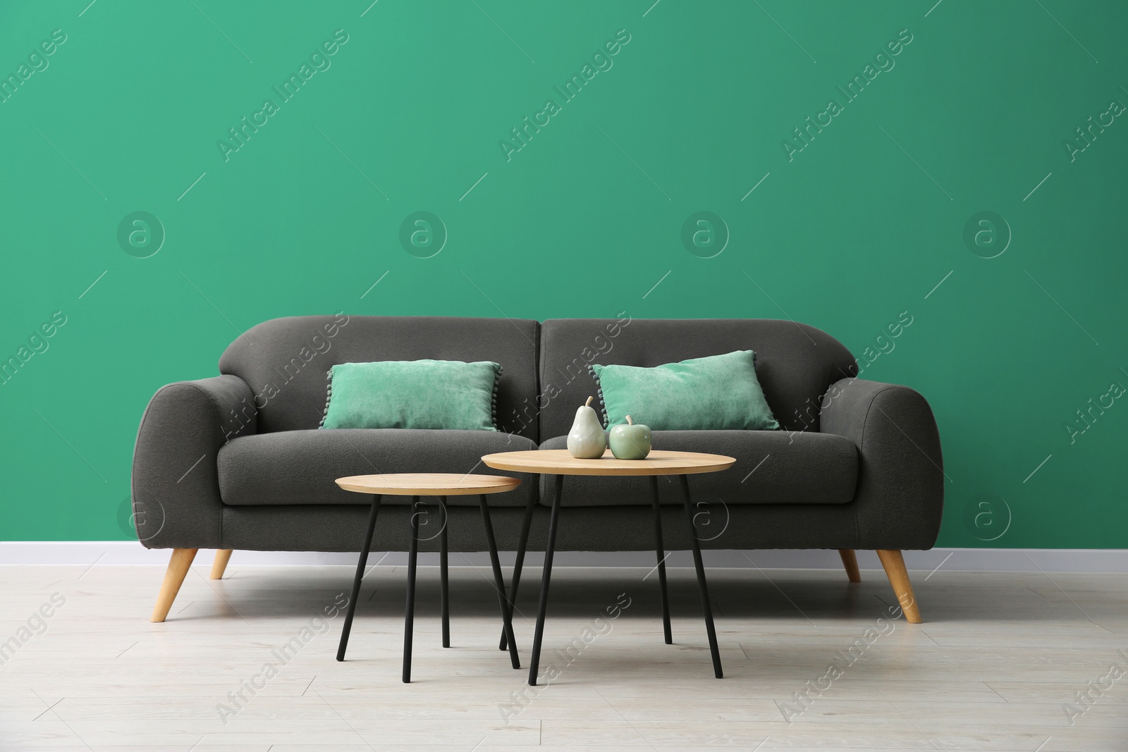 Image of Grey sofa and nesting tables near sea green color wall in room