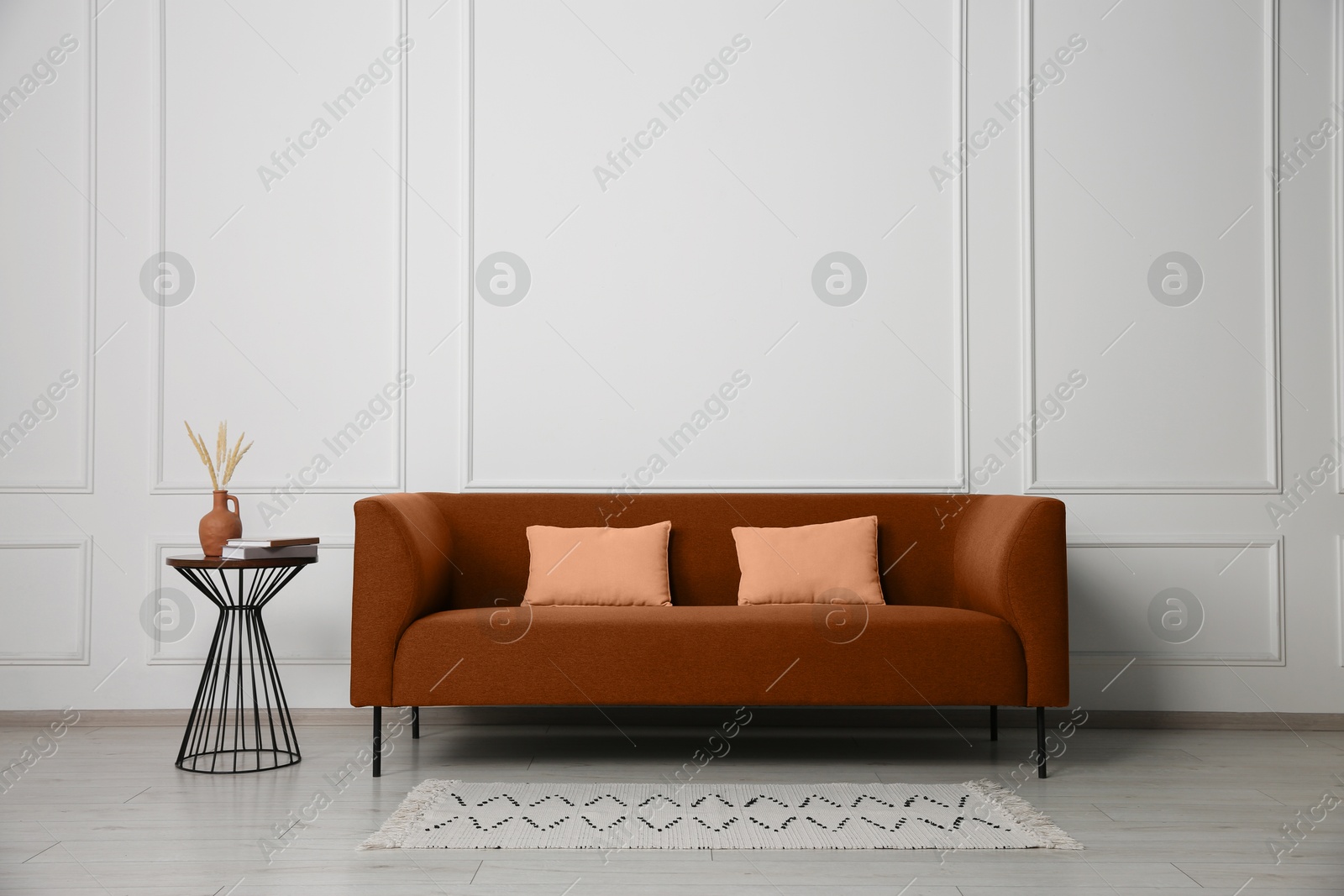 Image of Comfortable brown sofa and table near white wall in room