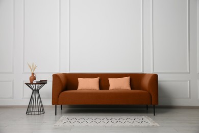 Image of Comfortable brown sofa and table near white wall in room